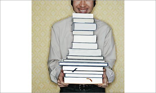 Picture of man holding an unfeasibly large stack of books.